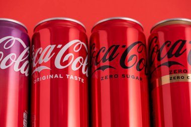 Lviv, Ukrayna - 05 Mayıs 2025: Coca Cola 'nın demir kutuları: klasik, sıfır şeker, sıfır şeker sıfır kafein, kırmızı arka planda kiraz aroması. Üst görünüm