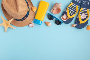 Deniz kabukları, güneş kremi, hasır şapka, sandalet ve mavi arka planda güneş gözlüğü. Üst Manzara. Boşluğu kopyala