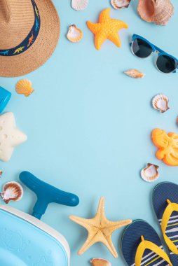 Çocukların kumsal valizleri, kalıpları, hasır şapkaları ve mavi arka planda güneş gözlüklerinin olduğu renkli ve eğlenceli bir yaz kurgusu. Üst Manzara. Boşluğu kopyala