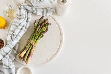 Beyaz masada baharat ve limonla taze kuşkonmaz filizleri. Üst görünüm