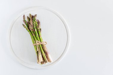 Beyaz masaya bağlanmış taze kuşkonmaz. Üst görünüm