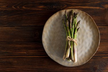 Kuşkonmaz kahverengi tabağa bağlanmış, kırsal masada. Üst görünüm