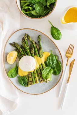 Izgara kuşkonmaz, ıspanak ve beyaz masada Hollandaise sosuyla haşlanmış yumurta. Üst görünüm