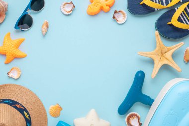 Çocukların kumsal valizleri, kalıpları, hasır şapkaları ve mavi arka planda güneş gözlüklerinin olduğu renkli ve eğlenceli bir yaz kurgusu. Üst Manzara. Boşluğu kopyala