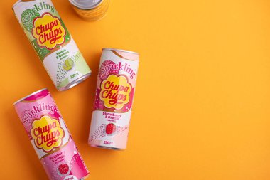 Lviv, Ukrayna - 6 Mayıs 2025: Demir içki kutuları Chupa Chups: sarı arka planda çilek, kavun, mango ve ahududu aroması. Üst görünüm