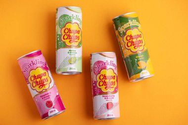 Lviv, Ukrayna - 6 Mayıs 2025: Demir içki kutuları Chupa Chups: sarı arka planda çilek, kavun, mango ve ahududu aroması. Üst görünüm