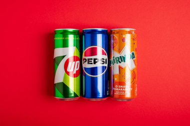 Lviv, Ukrayna - 25 Mayıs 2025: Pepsi Classic Soda, 7up ve Mirinda Cans kırmızı arka planda. Üst görünüm