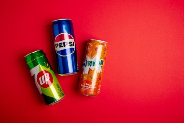 Lviv, Ukrayna - 25 Mayıs 2025: Pepsi Classic Soda, 7up ve Mirinda Cans kırmızı arka planda. Üst görünüm