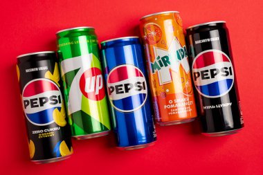 Lviv, Ukrayna - 25 Mayıs 2025: Pepsi Zero Sugar Soda, Classic Soda, Zero Sugar Citrus Soda, 7up ve Mirinda Cans kırmızı arka planda. Üst görünüm