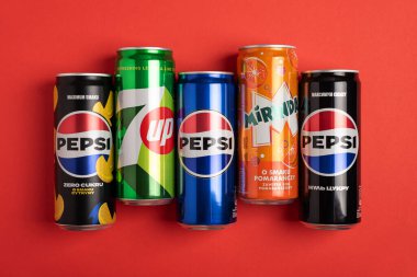 Lviv, Ukrayna - 25 Mayıs 2025: Pepsi Zero Sugar Soda, Classic Soda, Zero Sugar Citrus Soda, 7up ve Mirinda Cans kırmızı arka planda. Üst görünüm