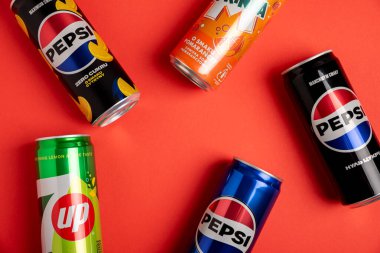 Lviv, Ukrayna - 25 Mayıs 2025: Pepsi Zero Sugar Soda, Classic Soda, Zero Sugar Citrus Soda, 7up ve Mirinda Cans 'in çerçevesi kırmızı arka planda. Üst görünüm