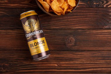 Lviv, Ukrayna - 15 Mayıs 2025: Kırsal arka planda patates cipsli Grimbergen Blonde birası. Üst görünüm