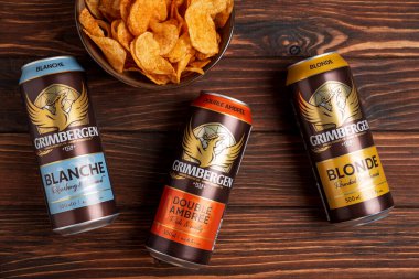 Lviv, Ukrayna - 15 Mayıs 2025: Grimbergen Blonde, Blanche ve Double Ambree biraları ve kırsal alanda patates cipsi. Üst görünüm