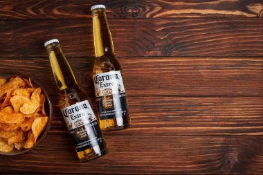 Lviv, Ukrayna - 15 Mayıs 2025: Kırsal arka planda iki bardak Corona Extra birası ve patates cipsi. Üst görünüm
