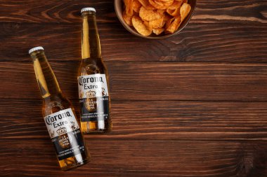 Lviv, Ukrayna - 15 Mayıs 2025: Kırsal arka planda iki bardak Corona Extra birası ve patates cipsi. Üst görünüm