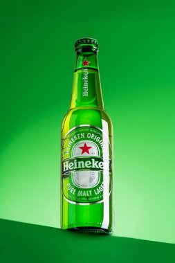 Lviv, Ukrayna - 25 Mayıs 2025: Yeşil arka planda bir şişe Heineken birası. Ön görünüm