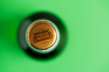 Lviv, Ukrayna - 25 Mayıs 2025: Yeşil arka planda Stella Artois 'in yakın plan bira şişesi. Üst görünüm