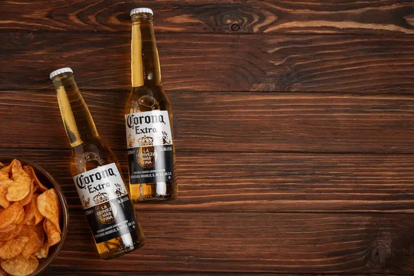 Lviv, Ukrayna - 15 Mayıs 2025: Kırsal arka planda iki bardak Corona Extra birası ve patates cipsi. Üst görünüm