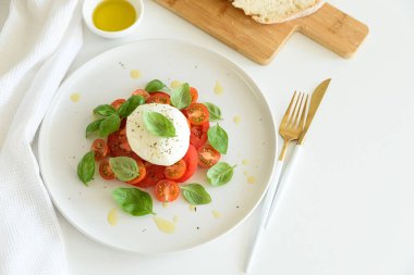 Mozarella, domates ve fesleğenli taze Caprese salatası, ekmekle servis edilir..