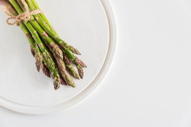 Beyaz masaya bağlanmış taze kuşkonmaz. Üst görünüm