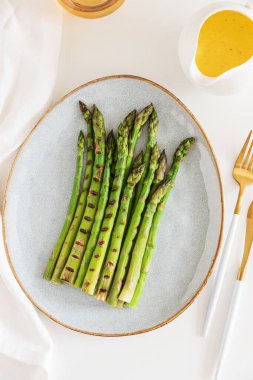Tabakta ızgara yeşil kuşkonmaz ve beyaz masada Hollandaise sosu. Üst görünüm