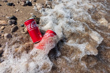 Kemer, Türkiye - Haziran 05, 2025: Okyanus suyu ile kayalık bir sahilde Coca-Cola kutuları. Üst görünüm