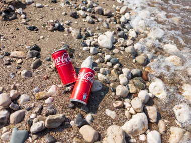Kemer, Türkiye - Haziran 05, 2025: Okyanus suyu ile kayalık bir sahilde Coca-Cola kutuları. Üst görünüm