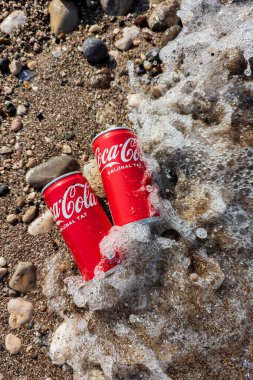 Kemer, Türkiye - Haziran 05, 2025: Okyanus suyu ile kayalık bir sahilde Coca-Cola kutuları. Üst görünüm