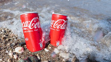 Kemer, Türkiye - Haziran 05, 2025: Okyanus suyu ile kayalık bir sahilde Coca-Cola kutuları. Ön görünüm