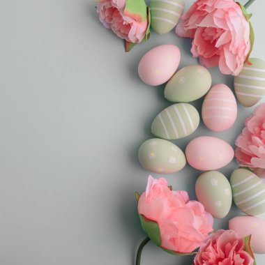 Paskalya yumurtaları ve pastel arka planda bahar çiçekleri. Üst görünüm