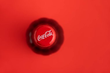 Lviv, Ukrayna - 19 Haziran 2025: Kırmızı arka planda bir Coca-Cola şişe kapağının yukarıdan aşağı görüntüsü.