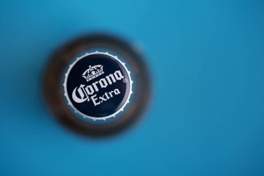 Lviv, Ukrayna - 19 Haziran 2025: Mavi arka planda bir Corona Extra bira şişesi kapağının yukarıdan aşağı görüntüsü.