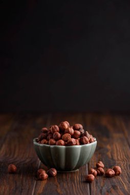 Koyu ahşap arka planda bir kasede fındık. Ön görünüm