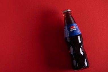 Lviv, Ukrayna - 6 Nisan 2025: Kırmızı arka planda duran Pepsi şişesi.