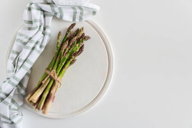 Beyaz masaya bağlanmış taze kuşkonmaz. Üst görünüm
