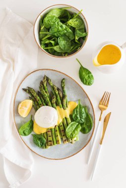 Izgara kuşkonmaz, ıspanak ve beyaz masada Hollandaise sosuyla haşlanmış yumurta. Üst görünüm