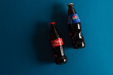 Lviv, Ukrayna - 6 Nisan 2025: Mavi arka planda yatan Coca Cola ve Pepsi şişeleri. Üst görünüm