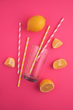 Limonata hazırlıyorum. Limonlar, pipetler ve parlak pembe arka planda bir bardak..