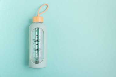 Mavi arka planda zaman çizgileri olan cam bir su şişesi..