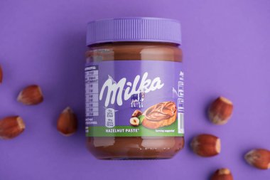 Lviv, Ukrayna - 19 Haziran 2025: Mor arka planda fındıklı Milka Fındık Ezmesi kavanozu. Üst görünüm