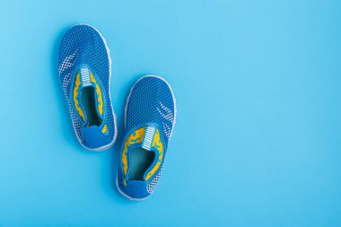 Mavi arka planda bir çift mavi ve sarı su ayakkabısı.