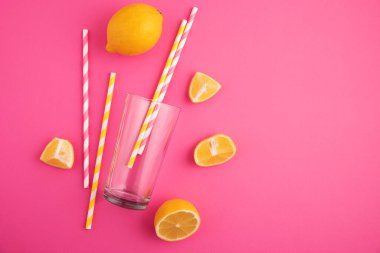Limonata hazırlıyorum. Limonlar, pipetler ve parlak pembe arka planda bir bardak..