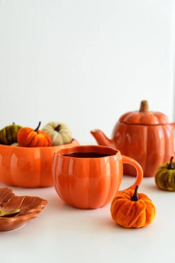 Balkabağı süslemeli sonbahar çay seti ve beyaz bir masada pasta..