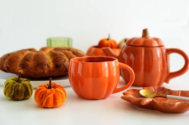 Balkabağı süslemeli sonbahar çay seti ve beyaz bir masada pasta..