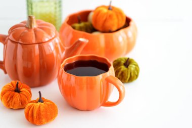 Balkabağı süslemeli sonbahar çay seti ve beyaz bir masada pasta..