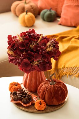 Sehpası, balkabağı ve çiçek aranjmanı olan Şükran Günü oturma odası dekoru..