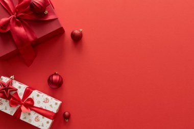 Kırmızı arka planda Noel hediyeleri ve süslemeler.