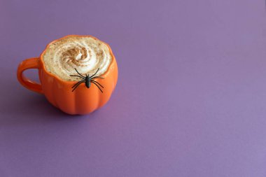 Cadılar Bayramı temalı düz yatış, balkabaklı latte ve mor arka planda örümcek ağları..