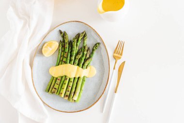 Limonlu ızgara yeşil kuşkonmaz ve beyaz masada Hollandez sosu. Üst görünüm