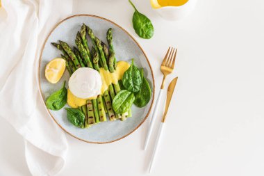 Izgara kuşkonmaz, ıspanak ve beyaz masada Hollandaise sosuyla haşlanmış yumurta. Üst görünüm